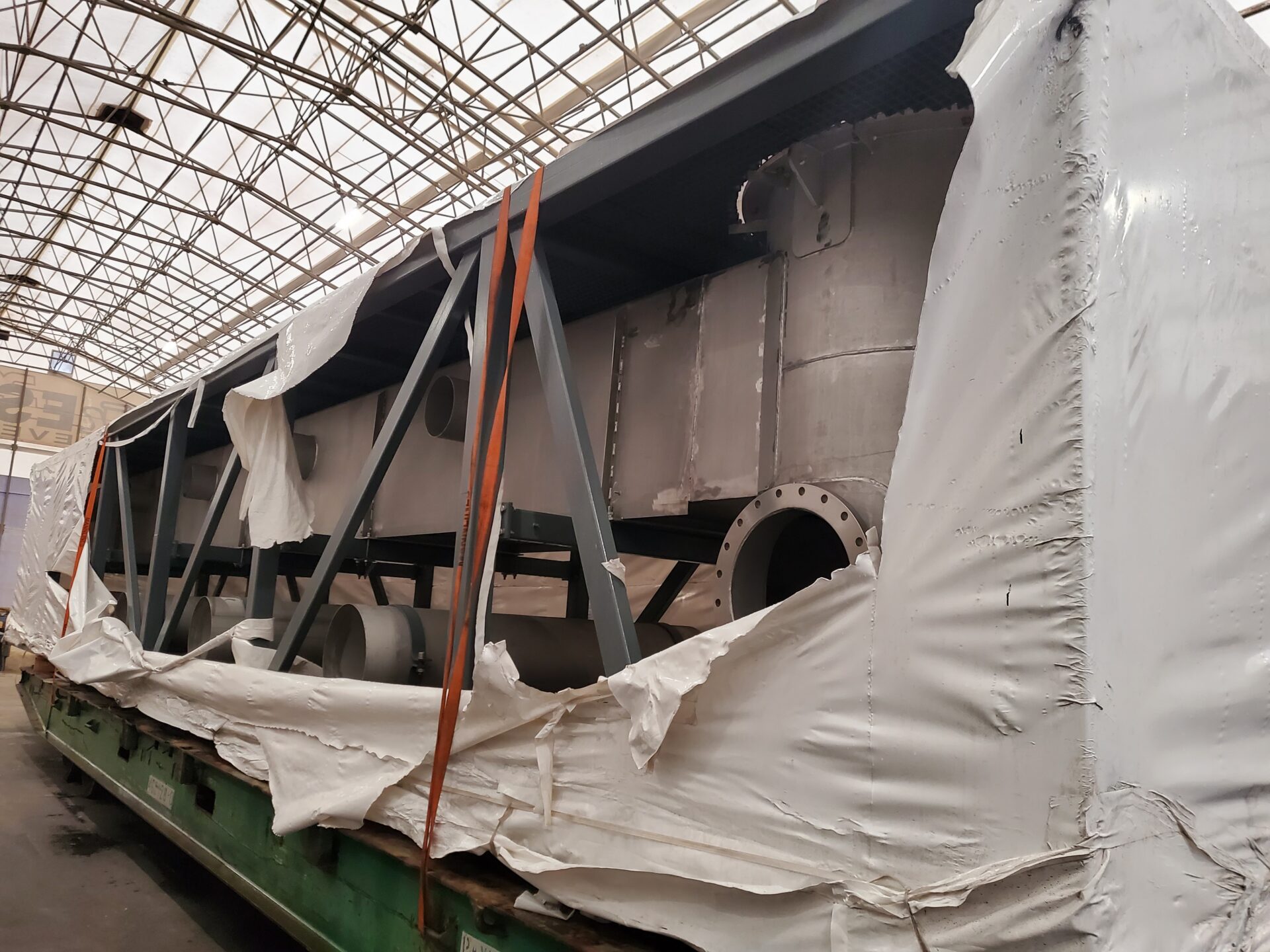 Damaged shrink wrap cover torn during transport on an industrial equipment load